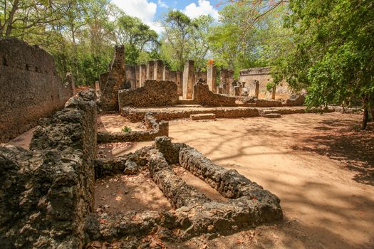 Ruins of ancient african city Gede (Gedi) in Watamu, Kenya with trees and sky in background.