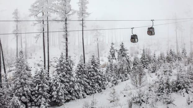 Two chairlift cabins passing each other on gray winter overcast day. Tatranska Lomnica ski resort, Slovakia