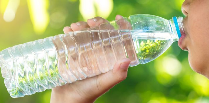 The boy is drinking water on a natural background