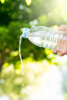 The boy is pouring water from the bottle on the natural background