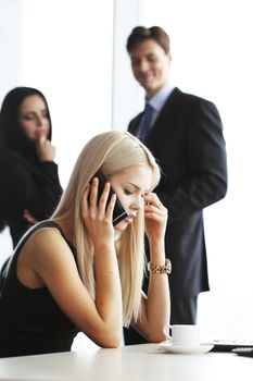 Young cute businesswoman talking on phone in office