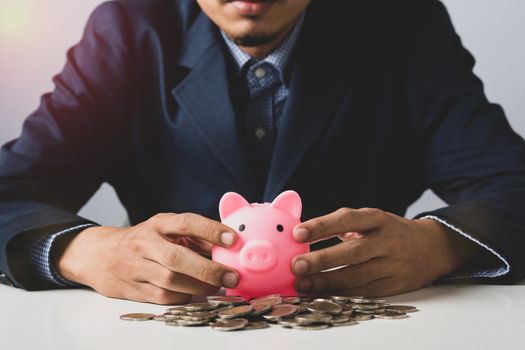 Hand of Business man holding coin put in piggy bank with money stack growing growth saving money, Concept invesment for financial freedom plan, business deposit to hope success