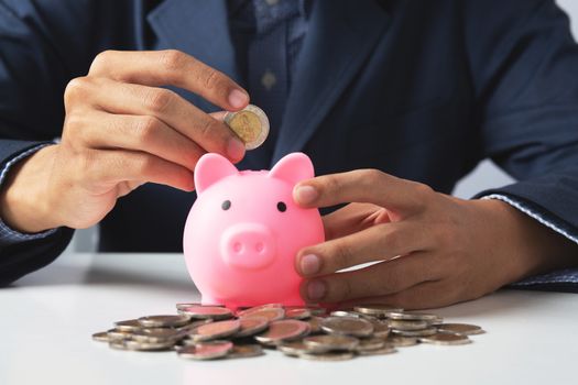 Hand of Business man holding coin put in piggy bank with money stack growing growth saving money, Concept invesment for financial freedom plan, business deposit to hope success 