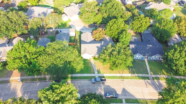 Drone view clean and empty neighborhood street with row of single family houses near Dallas, Texas, America. Suburban home with bungalow homes and large fenced backyard in early summer morning