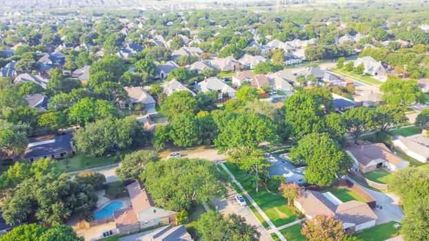 Aerial view an established neighborhood near Dallas, Texas, America in early summer morning. Suburban residential area with detached single family houses and large fenced backyard