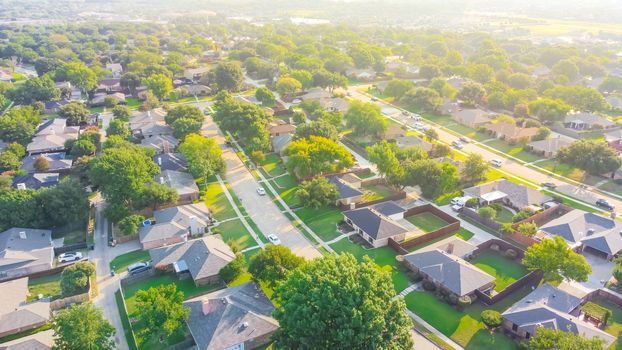 Urban sprawl near Dallas, Texas, USA with row of single family houses and large fenced backyard. Aerial view residential neighborhood subdivision surrounded by mature trees in early summer morning