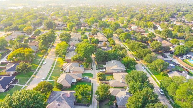 Drone view clean and empty neighborhood street with row of single family houses near Dallas, Texas, America. Suburban home with bungalow homes and large fenced backyard in early summer morning