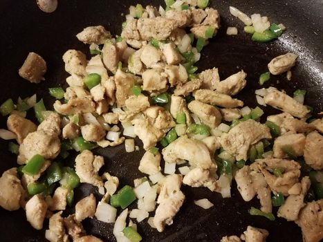 turkey meat cooking in frying pan with onion and green peppers