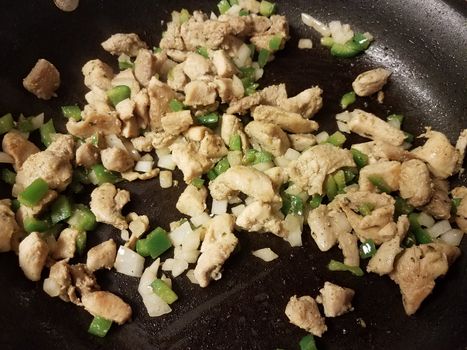 turkey meat cooking in frying pan with onion and green peppers