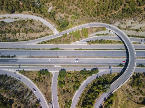 Day top panorama of European multi-level stack highway junction with passing cars through forest.