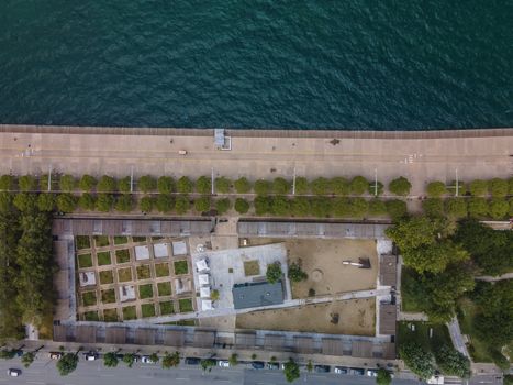 Day top panorama of European city with greenery & pedestrian area promenade before a calm seafront.