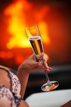 Champagne in woman hand on fireplace background