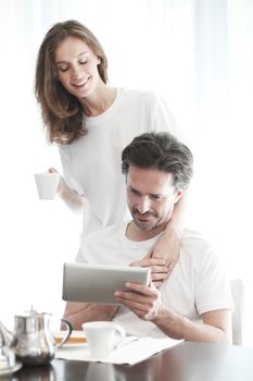 Couple having breakfast at home and using tablet