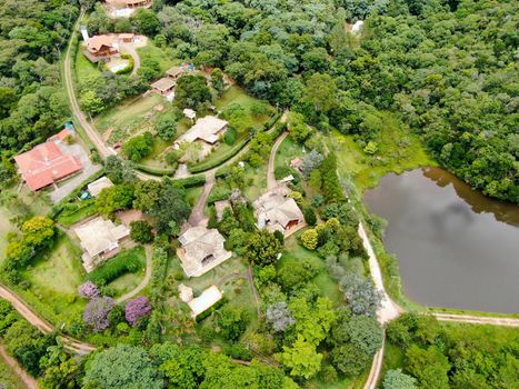 Aerial view of valley with lake, forest and villas in tropical country. Green mountain with forest on Brazil