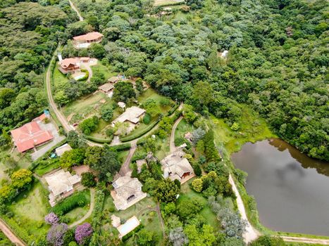 Aerial view of valley with lake, forest and villas in tropical country. Green mountain with forest on Brazil