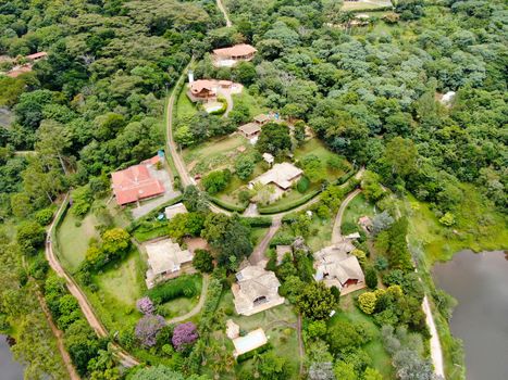 Aerial view of valley with lake, forest and villas in tropical country. Green mountain with forest on Brazil