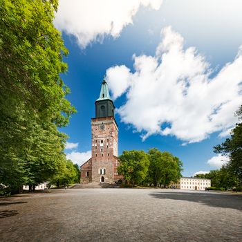 Turku Cathedral on sunny day with blue cloudy sky in background and empty square in foreground