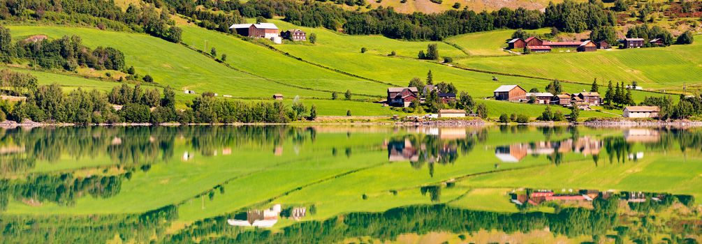 Norway country houses. Lake and meadows. Reflection in water. Nordic, Scandinavia, Europe travel