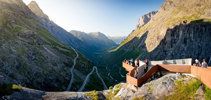 Rauma Municipality, Norway - 25 July, 2013: people on observation deck over Trollstigen mountain road. Serpentine road with cars and mountains in background. Popular tourist destination in Scandinavia, Europe.