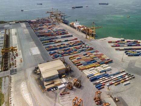 Top panorama of large motorized cranes on sea port, with containers on commercial berthing dock pier.