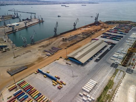Day top panorama of large motorized cranes on sea port, with cargo containers on commercial berthing dock pier.