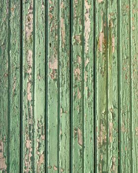 abstract pattern of old green grungy paint blisters on vertical wooden planks
