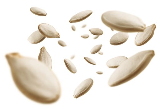 Pumpkin seeds levitate on a white background.