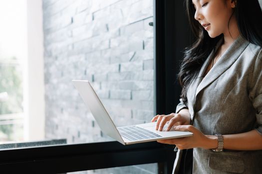 Portrait of smiling millennial businesswoman holding laptop computer looking at camera.