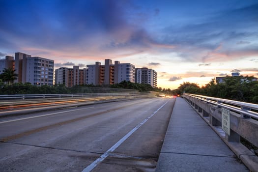 Light trails on the Overpass of Bluebill Avenue leading toward Delnor Wiggins State Park at sunset in Naples, Florida.