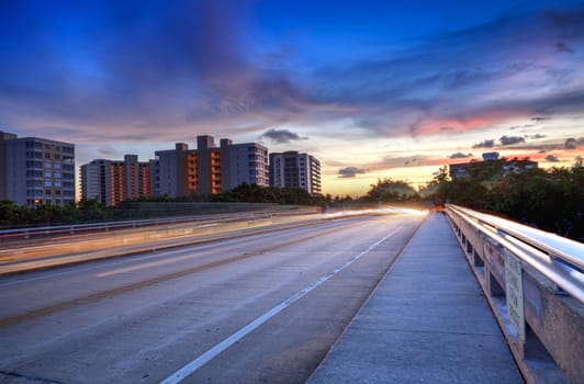 Light trails on the Overpass of Bluebill Avenue leading toward Delnor Wiggins State Park at sunset in Naples, Florida.