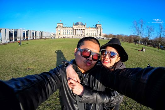 Young Couple Tourists selfie with mobile phone near the Reichstag building (german government) in Berlin, Germany