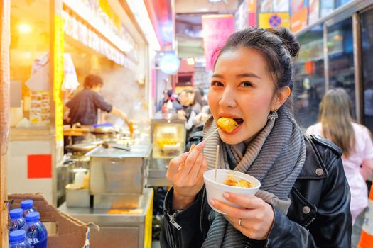 Chinese Asian young female model eating Chinese Steamed Dumpling on Street in Hong Kong