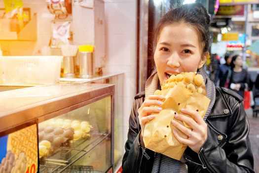 Young woman eating waffle street food in hong kong