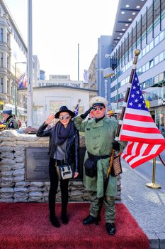 BERLIN, GERMANY - March 18, 2017: Unidentified young woman and men dressed as American soldiers stand near the checkpoint Charlie.The most famous crossing point between East and West Berlin after WW2.