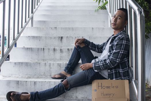 Unhappy homeless man sitting on overpass