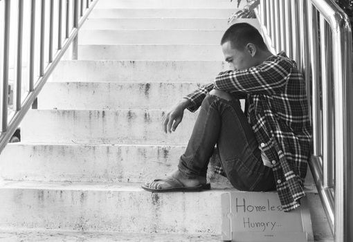 Unhappy homeless man sitting on overpass