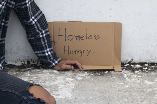 Close-up of homeless and hungry street person asking for help on the sidewalk