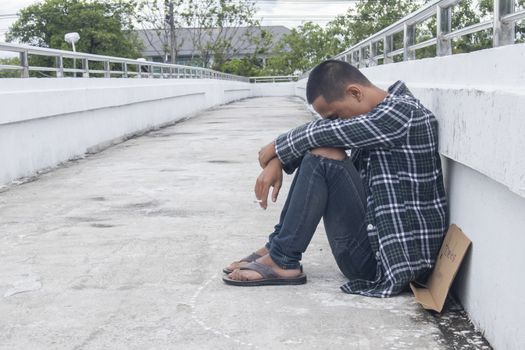 Unhappy homeless man sitting on overpass