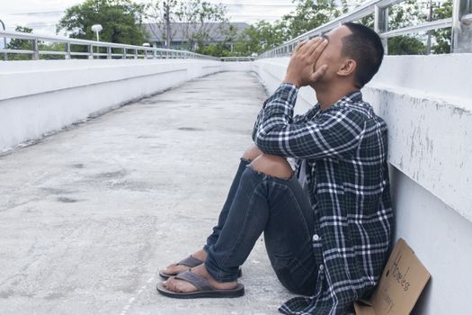 Unhappy homeless man sitting on overpass