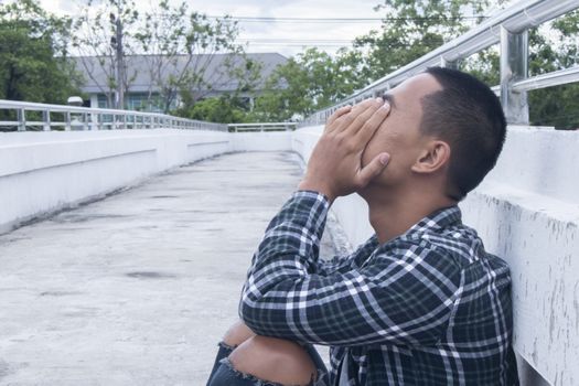 Unhappy homeless man sitting on overpass