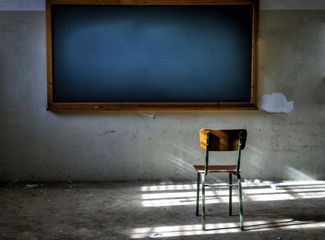 Abandoned classroom with chair in front of the vintage blackboard