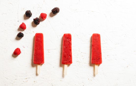 Delicious strawberry popsicles on light background