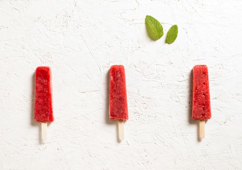 Delicious strawberry popsicles on light background