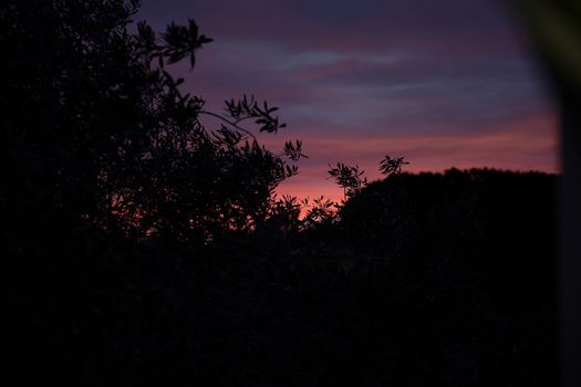 Early morning behind mountains, dark landscape, sunrise sky.
