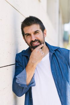 Cheerful bearded male with hand on chin while looking camera