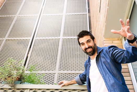 Bearded male with stretched arms looking to camera while smiling