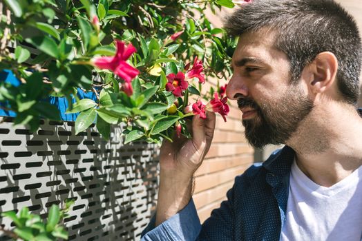 Portrait of bearded male smelling flowers in a city street