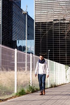 Young casual wear male walking on the street against business district