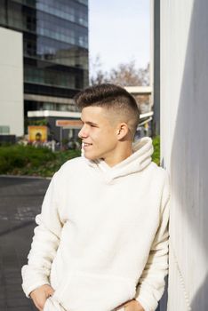 Portrait of young male with hands on pocket leaning on wall outdoors