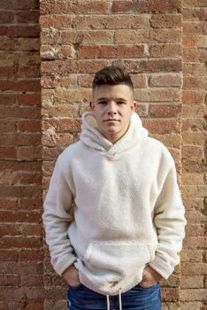 Portrait of young male with hands on pocket leaning on wall outdoors